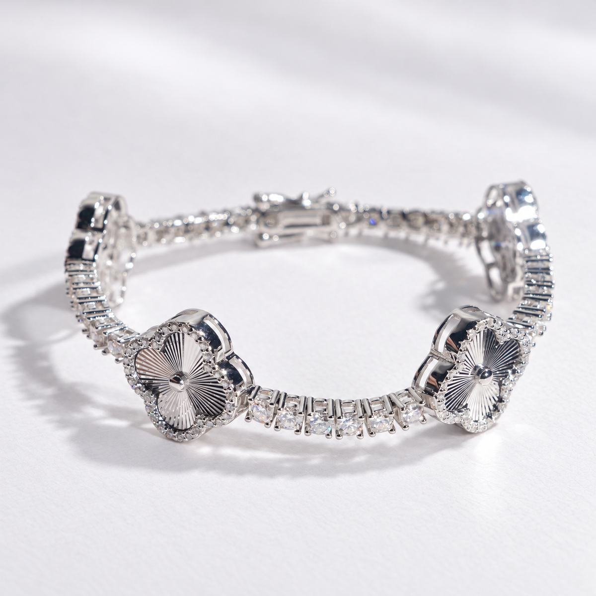 Silver-tone engraved clover tennis bracelet on plain white paper