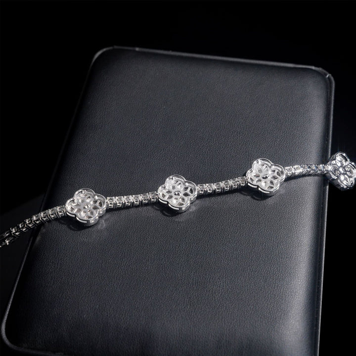 Reverse of a silver-tone clover tennis bracelet showing open back settings on a black display