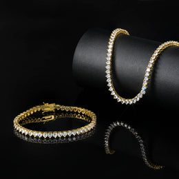 Gold-tone tennis bracelets on a black stand and reflective surface