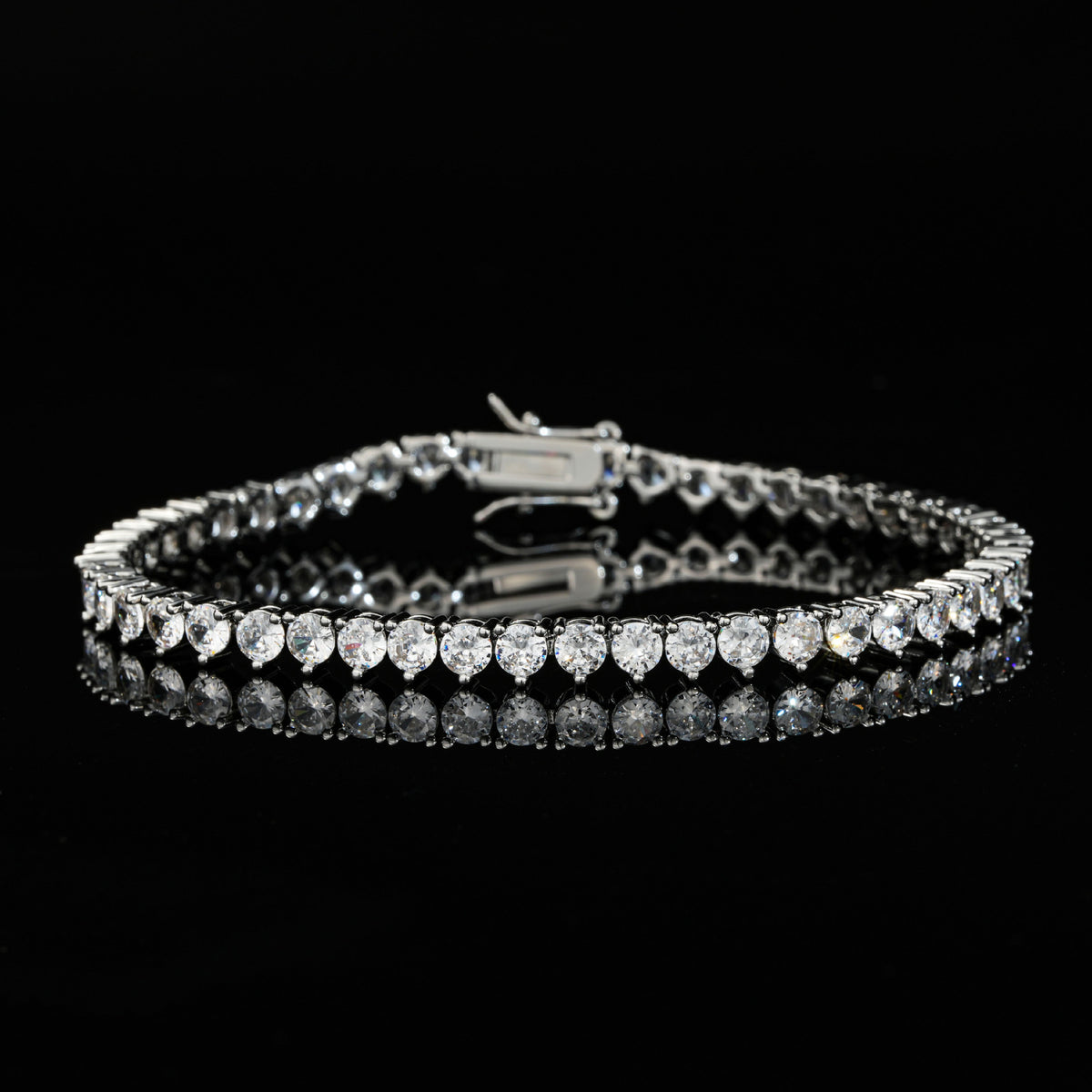 Silver-tone tennis bracelet with round stones on a reflective black surface