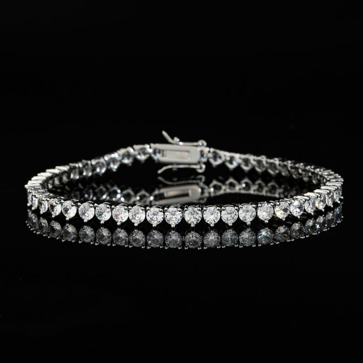 Silver-tone tennis bracelet with round stones on a reflective black surface