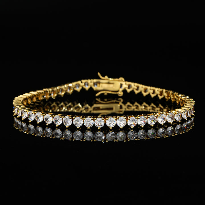 Gold-tone tennis bracelet with round stones on a reflective black surface