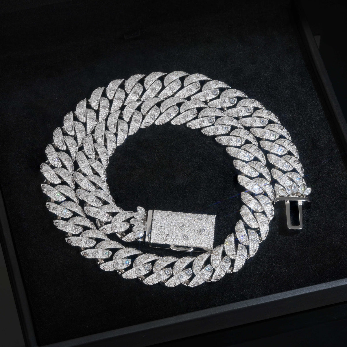 Silver-tone Cuban necklace coiled on a black tray with its box clasp open