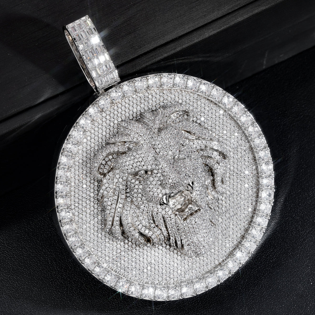 Silver-tone lion medallion pendant resting diagonally on a black box