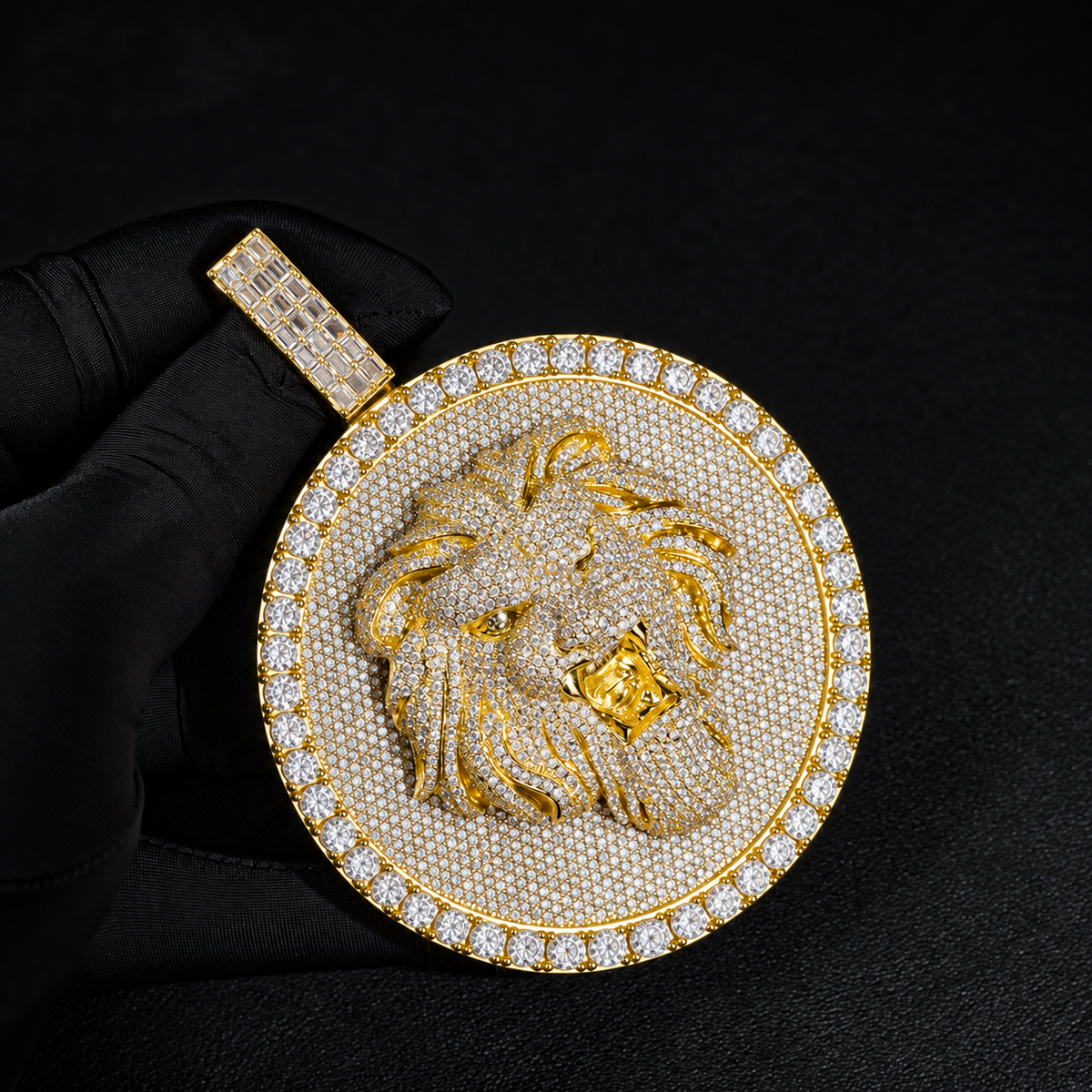 Gold-tone lion medallion pendant held by black-gloved fingers