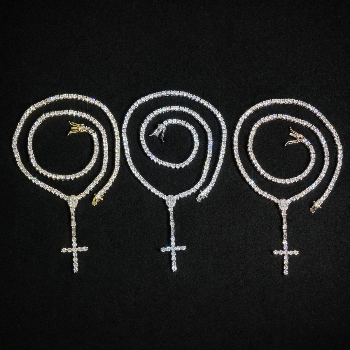 Gold, Silver and Rose Gold slender cross drop tennis necklaces in coils on black