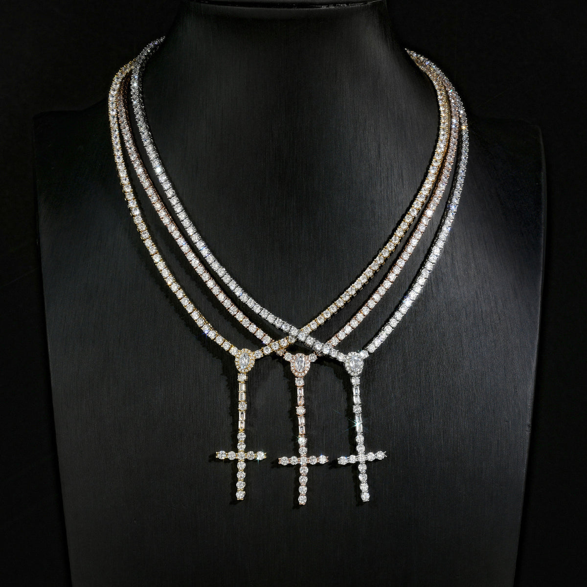 Gold, Silver and Rose Gold slender cross drop necklaces displayed on a black bust