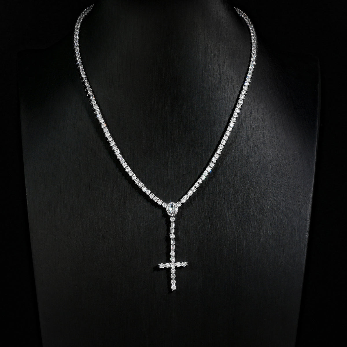 Slender silver-tone cross drop tennis necklace on a black display bust