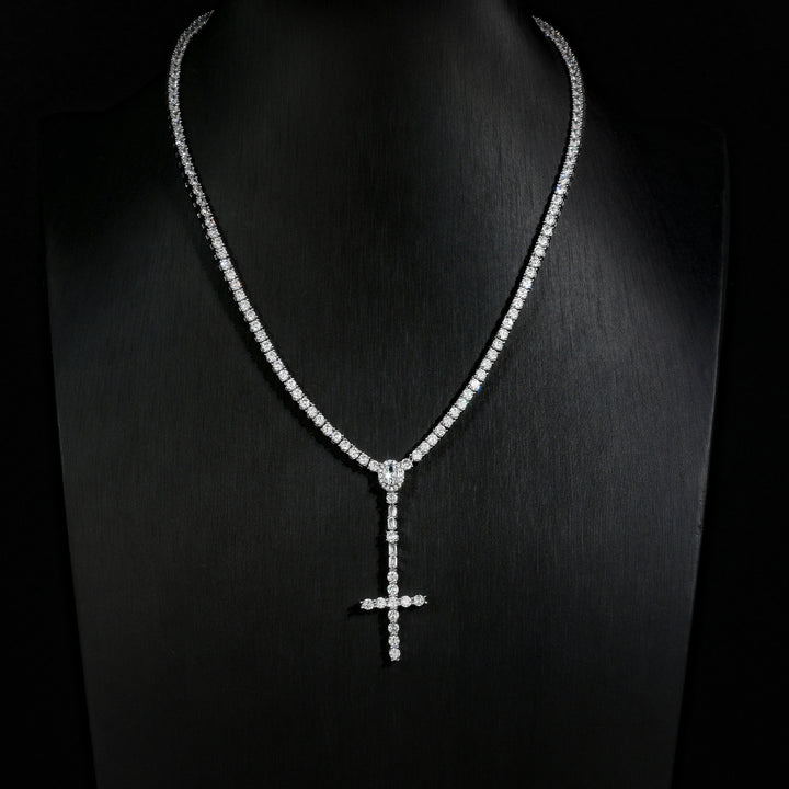 Slender silver-tone cross drop tennis necklace on a black display bust
