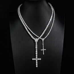 Comparison of slender and wider silver-tone cross drop tennis necklaces on a black display bust