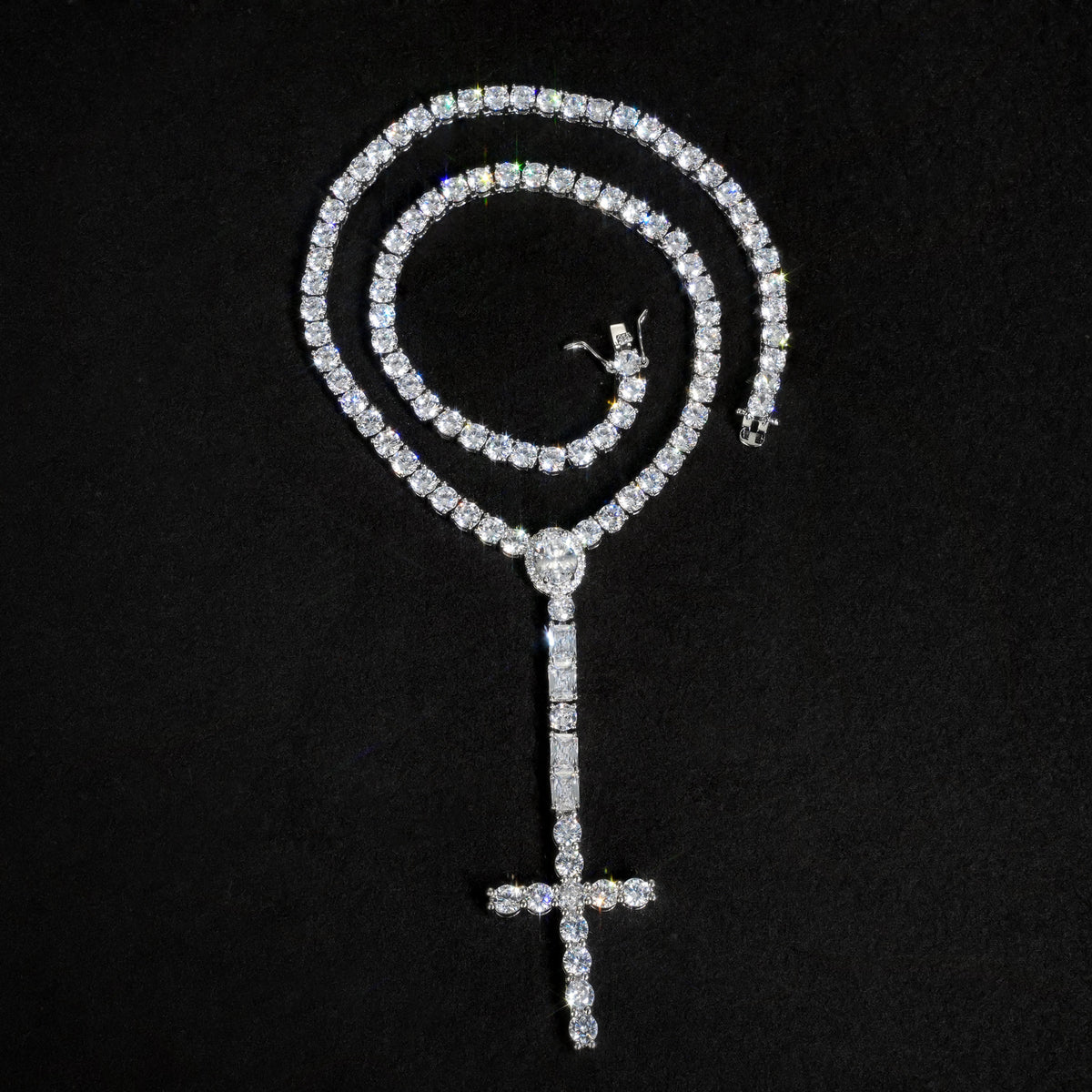 Silver-tone cross drop tennis necklace coiled above its long stone-set drop