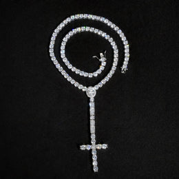 Silver-tone cross drop tennis necklace coiled above its long stone-set drop