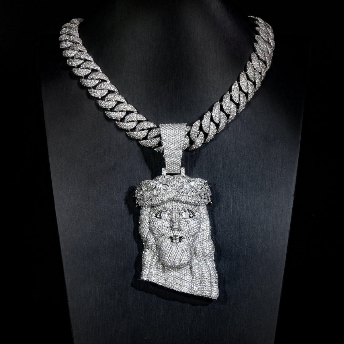 Silver-tone crowned Jesus pendant on a black display bust