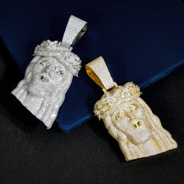 Silver-tone and gold-tone crowned Jesus pendants angled on a dark blue display