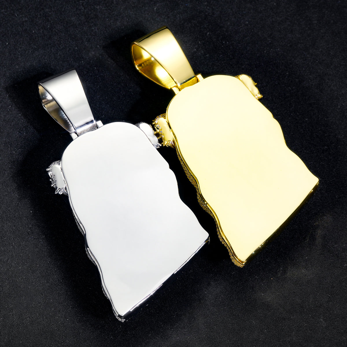 Back views of silver-tone and gold-tone Jesus pendants on black fabric
