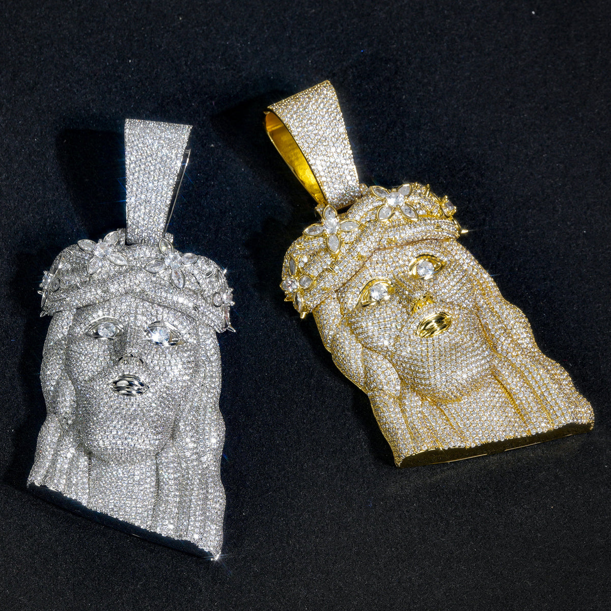 Silver-tone and gold-tone crowned Jesus pendants side by side on black fabric