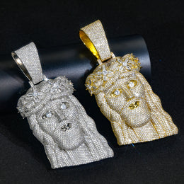 Angled front views of silver-tone and gold-tone crowned Jesus pendants on a black display