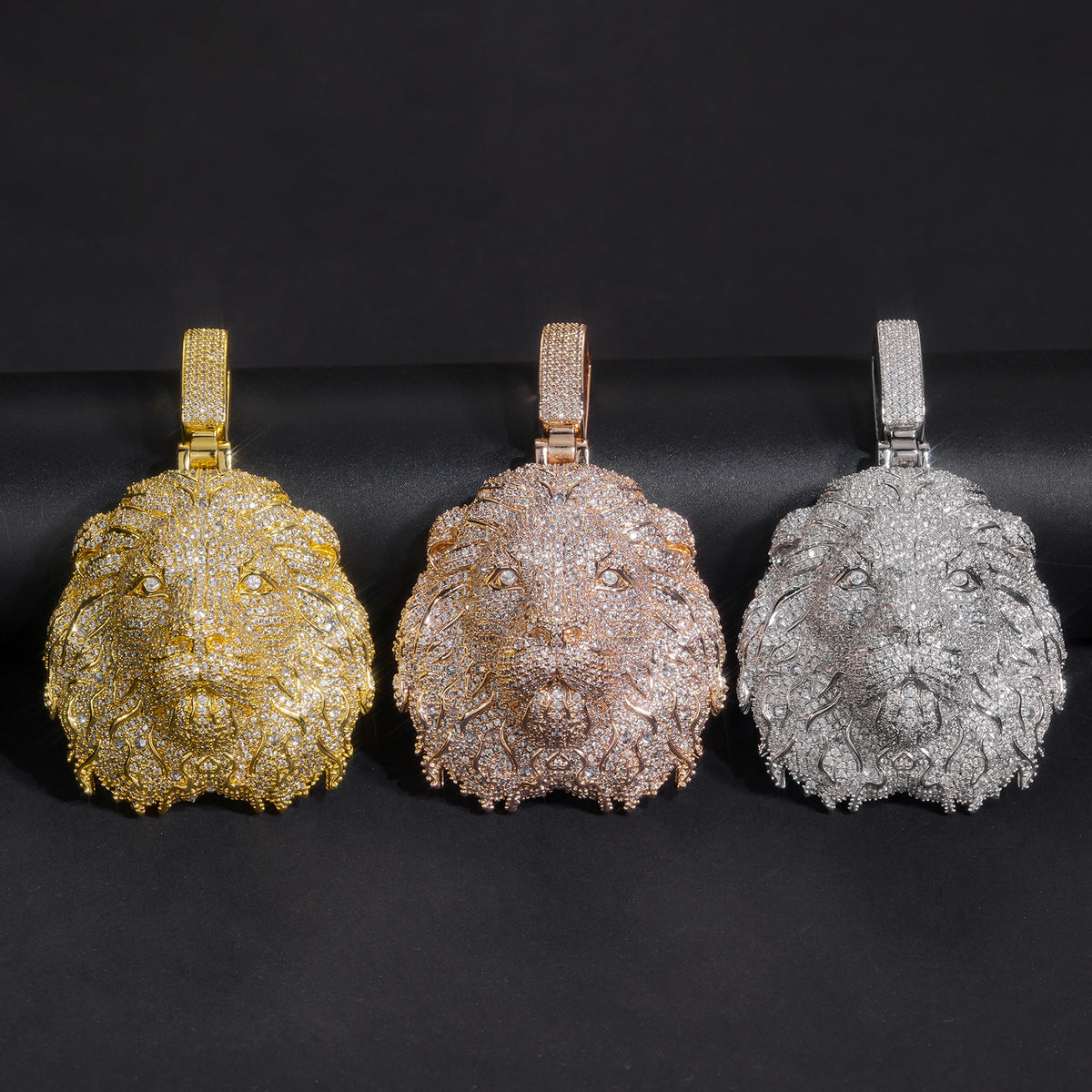Three lion head pendants in gold-tone, rose-gold-tone and silver-tone on black velvet