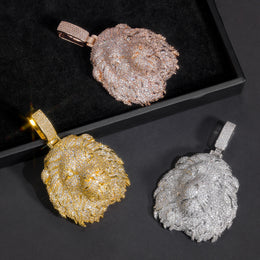 Rose-gold-tone lion head pendant above gold-tone and silver-tone pendants in a box