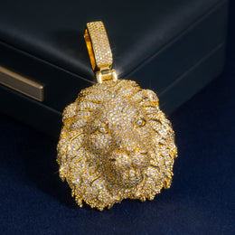 Close-up of a gold-tone lion head pendant on a dark blue surface