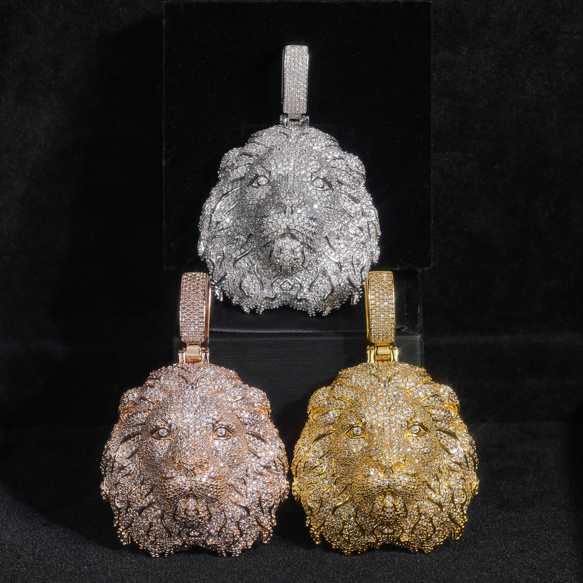 Silver-tone, gold-tone and rose-gold-tone lion head pendants arranged in a black box