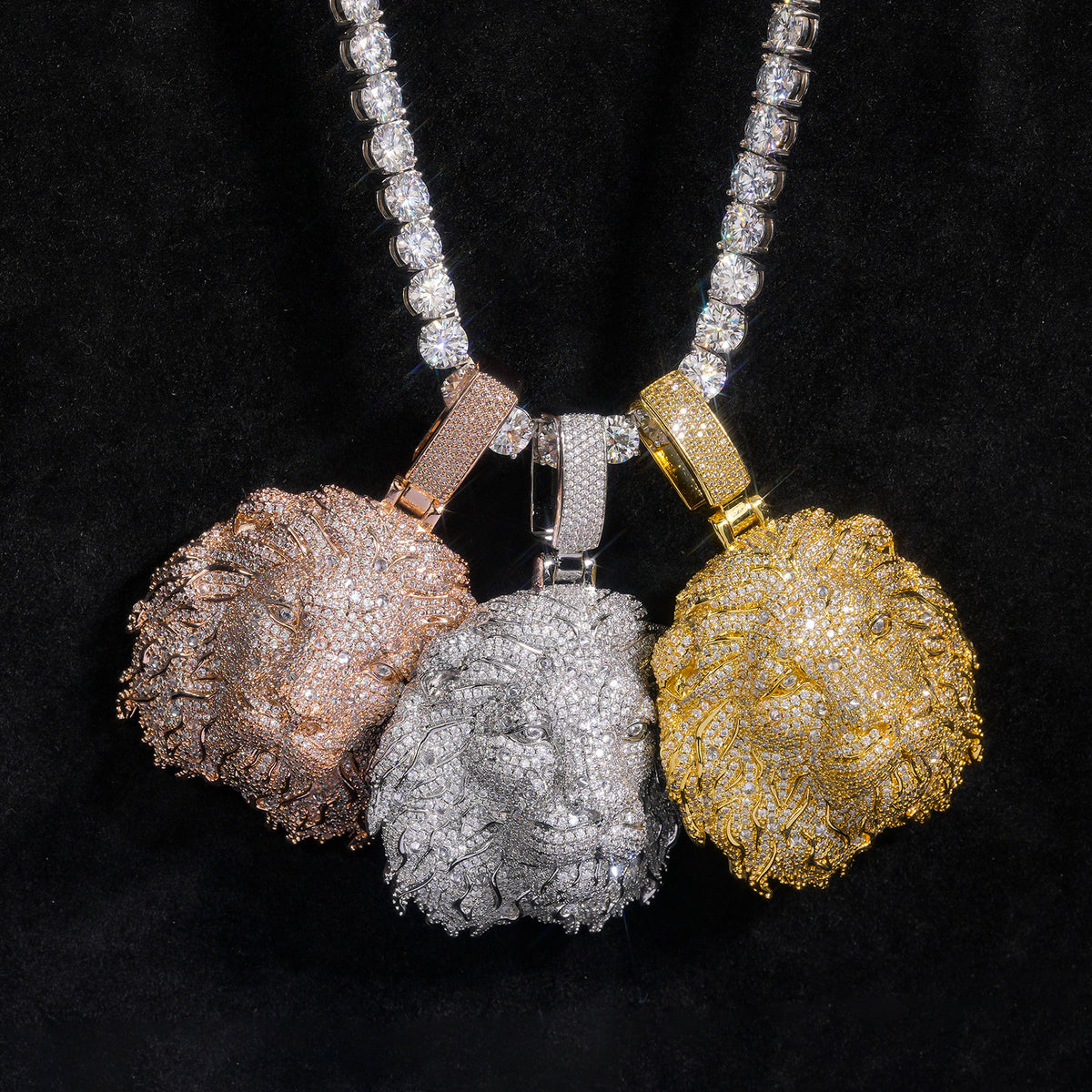 Three stone-set lion head pendants displayed together on black fabric