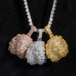 Three stone-set lion head pendants displayed together on black fabric