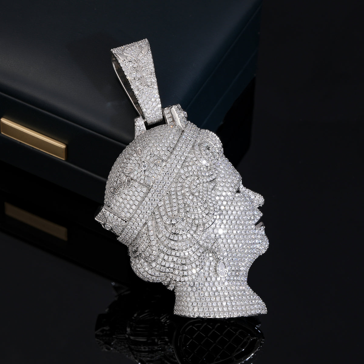 Silver-tone queen portrait pendant showing its stone-covered side on a black reflective surface