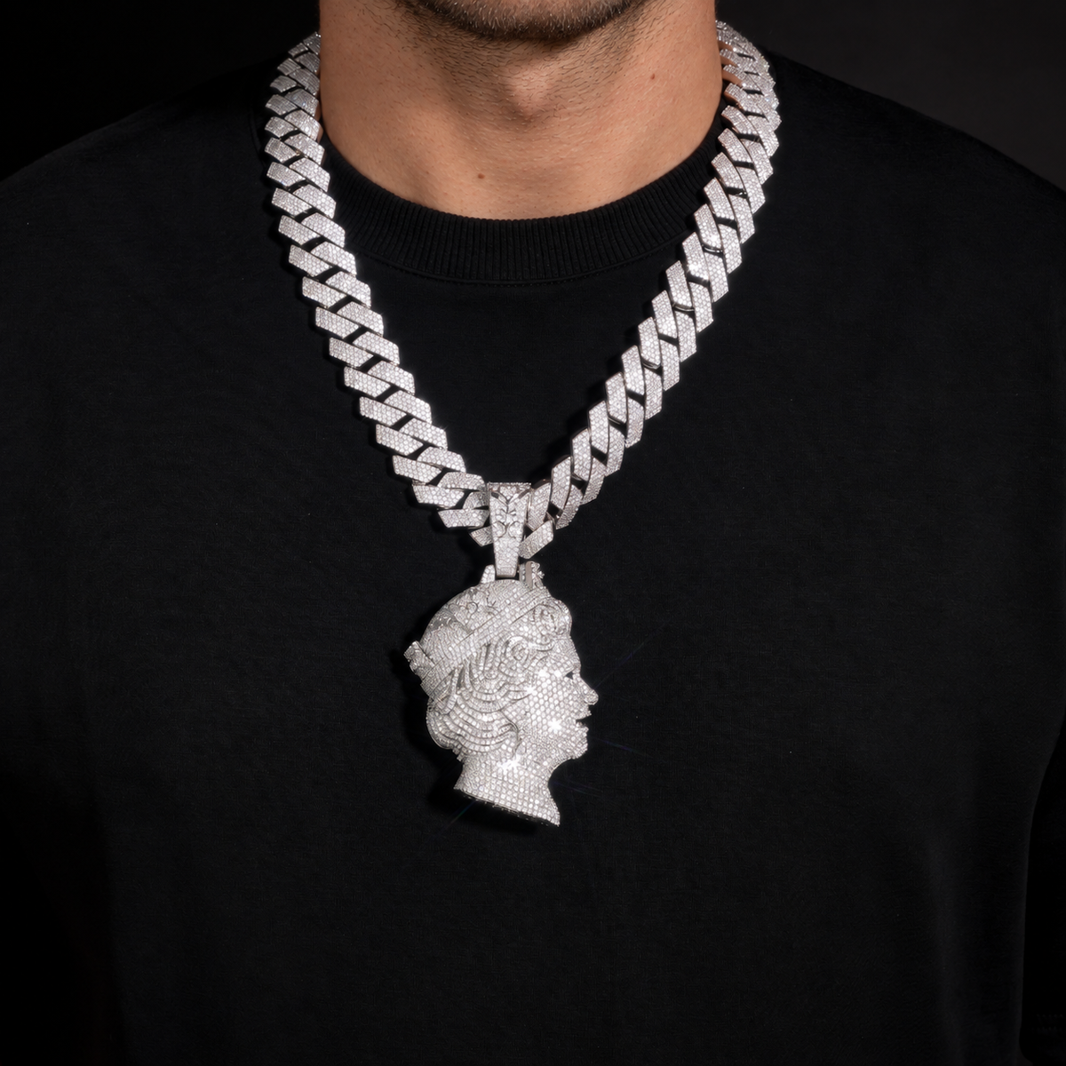 Model wearing a silver-tone iced queen portrait pendant over a black crew-neck shirt
