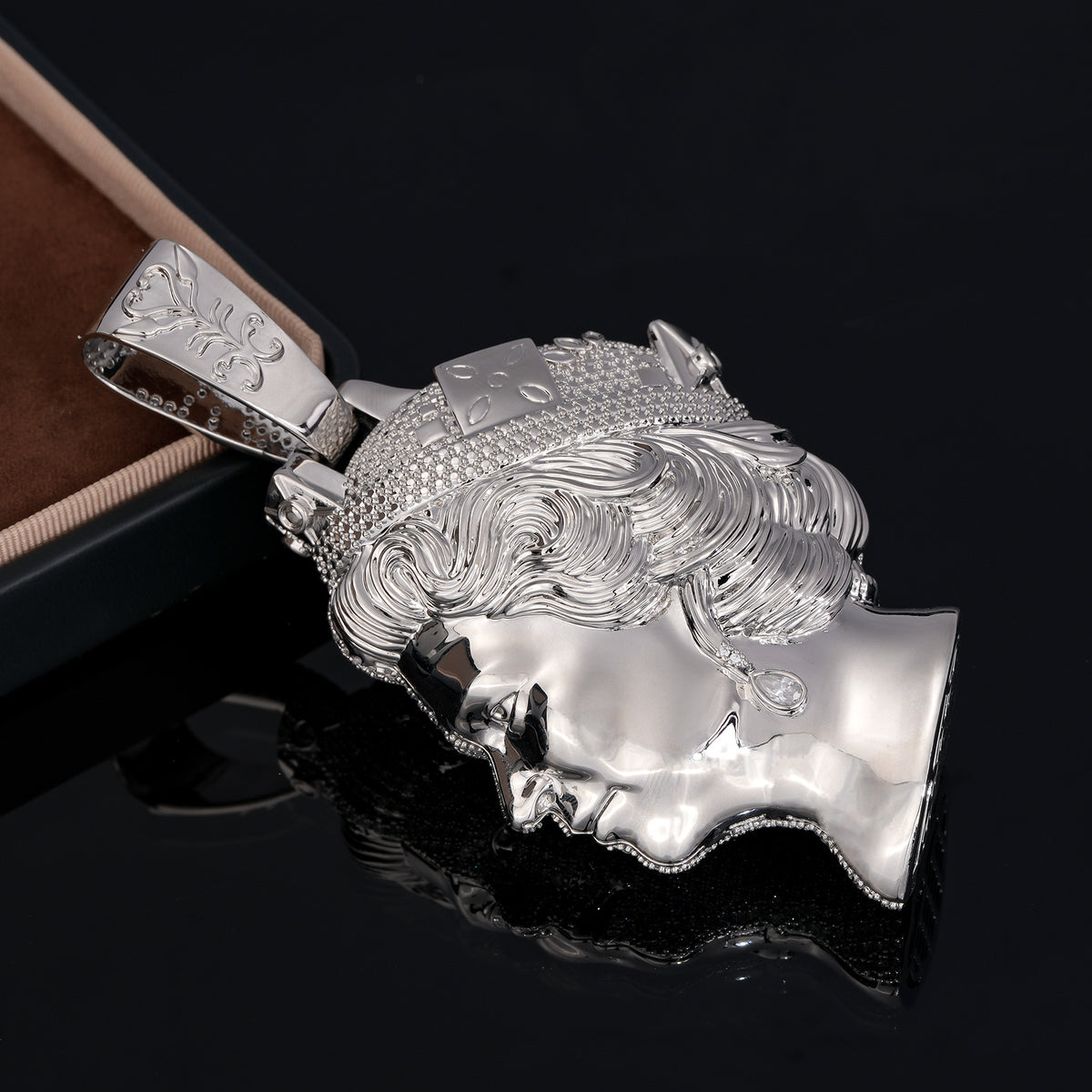 Silver-tone queen portrait pendant lying sideways with polished face and curled hair visible