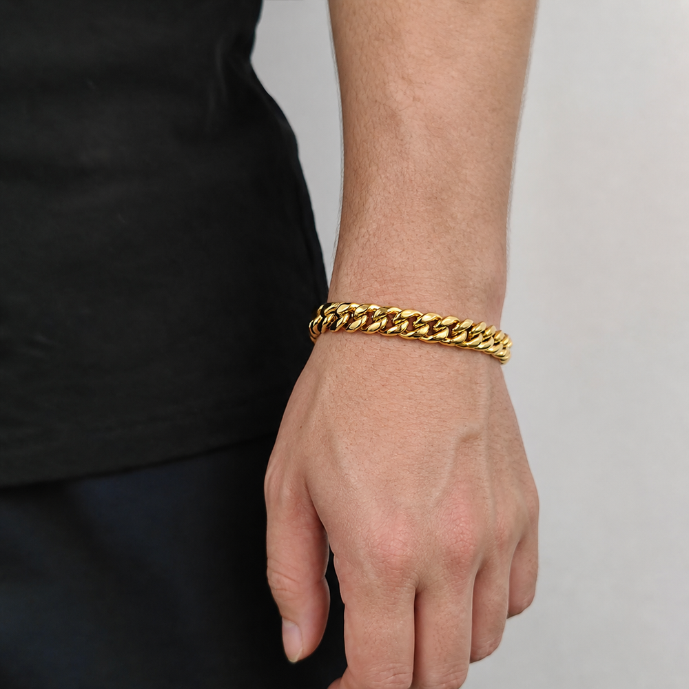 Gold-tone Cuban link bracelet worn on the wrist beside black clothing