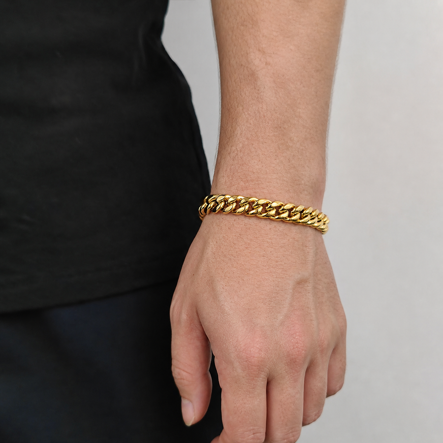 Gold-tone Cuban link bracelet worn on the wrist beside black clothing
