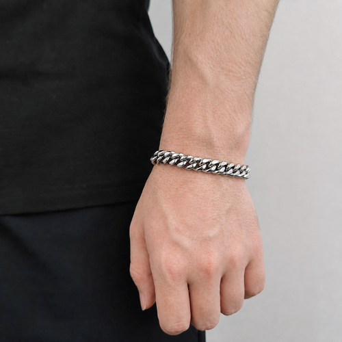 Silver-tone Cuban link bracelet worn on the wrist beside black clothing