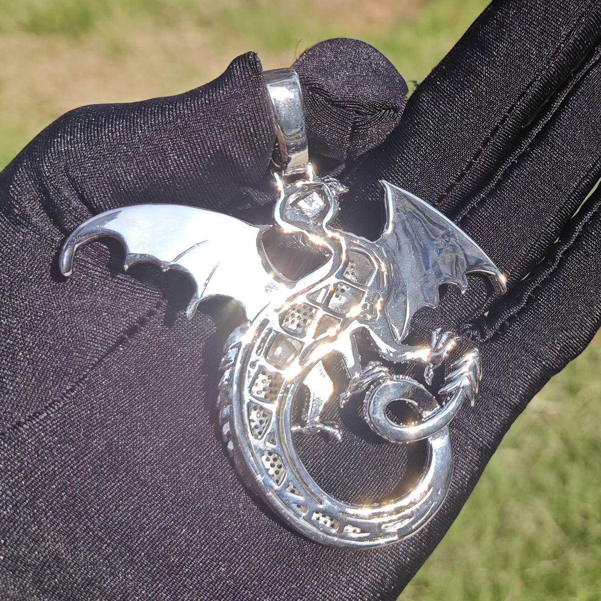 Back of a silver-tone dragon pendant showing the openwork body and smooth wings
