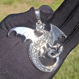 Back of a silver-tone dragon pendant showing the openwork body and smooth wings