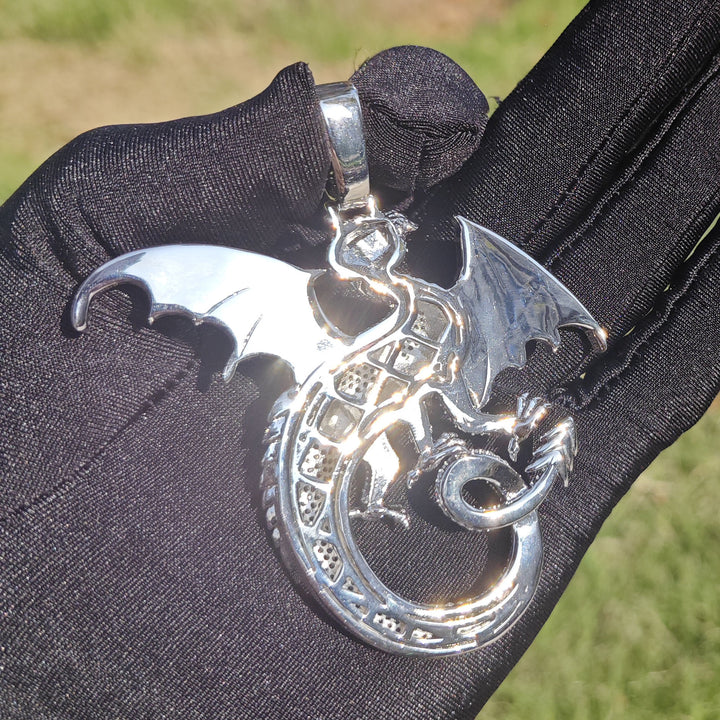 Back of a silver-tone dragon pendant showing the openwork body and smooth wings