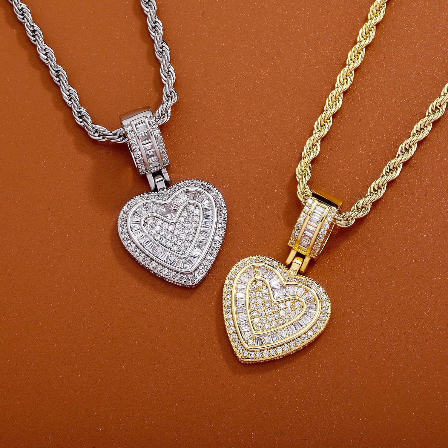 Gold and silver baguette iced double heart pendants on a brown background