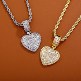 Gold and silver baguette iced double heart pendants on a brown background