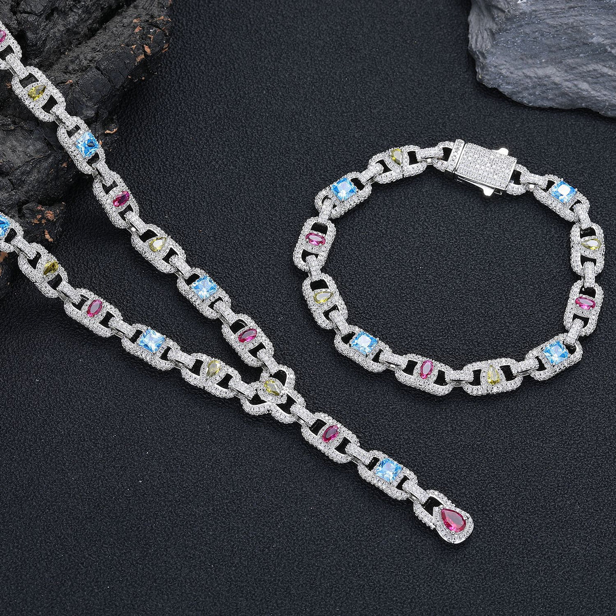 Silver-tone lariat necklace and matching bracelet arranged beside a dark rock