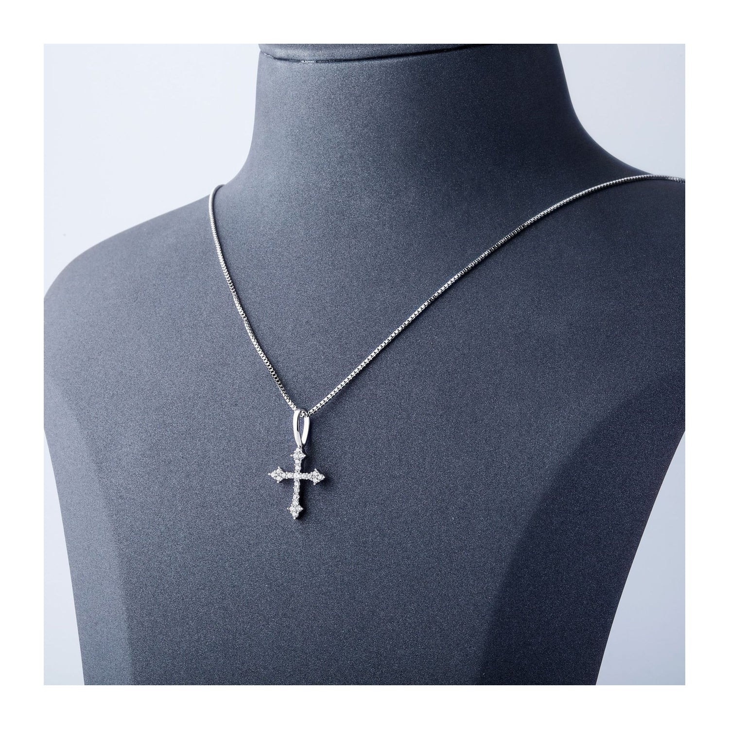 Silver iced ornate cross pendant displayed on a black bust