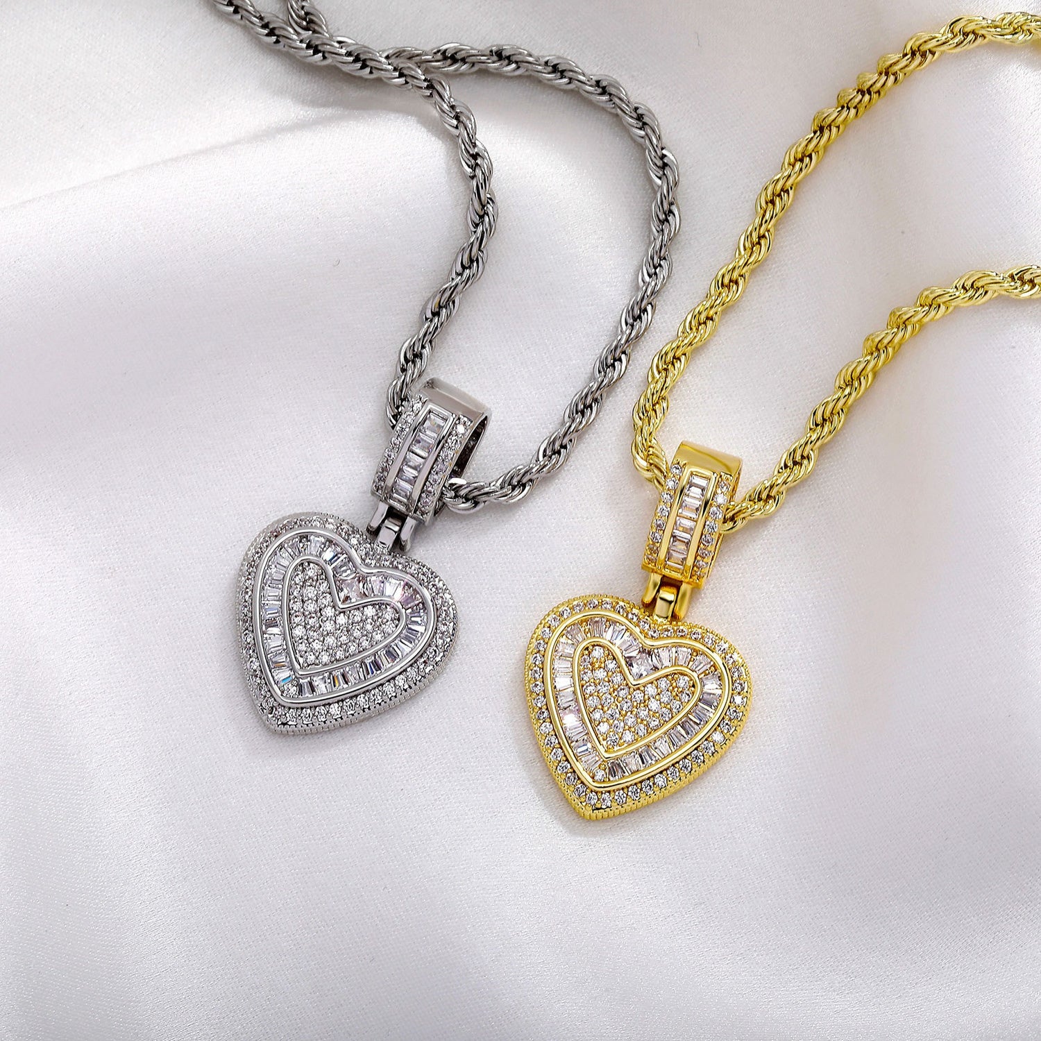 Gold and silver baguette iced double heart pendants on white fabric