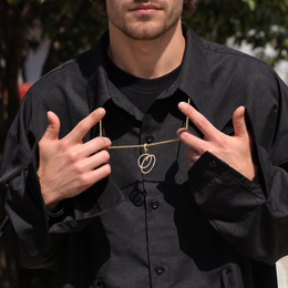 Model holding a gold-tone cubic zirconia script letter O pendant outdoors