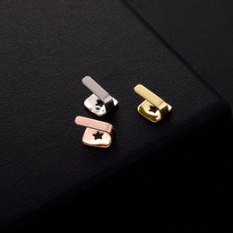 Gold, Silver and Rose Gold bar tooth caps showing star-shaped openings on black textured fabric