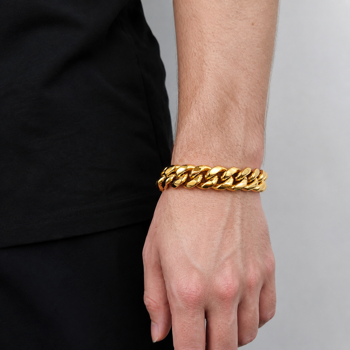 Gold-tone wide Cuban link bracelet worn on the wrist beside black clothing