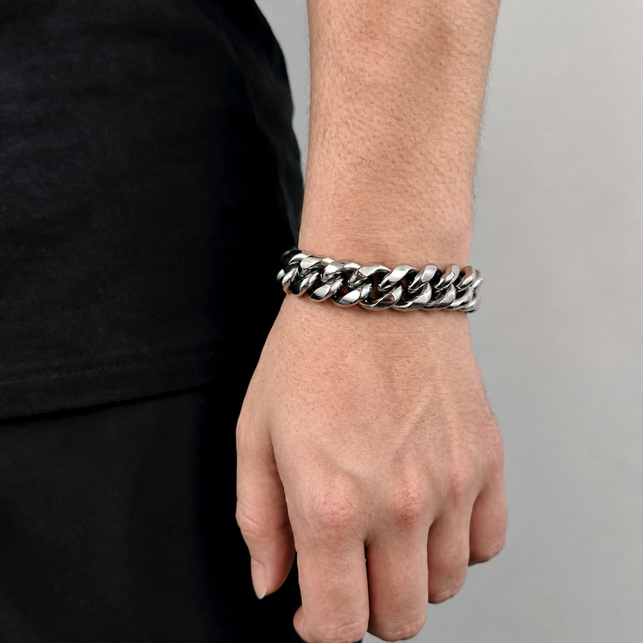 Silver-tone wide Cuban link bracelet worn on the wrist beside black clothing