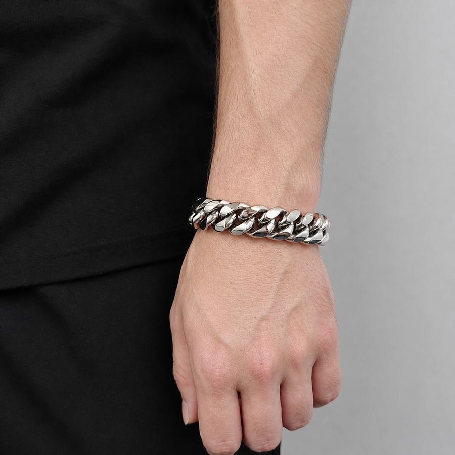 Silver-tone wide Cuban link bracelet worn on the wrist beside black clothing