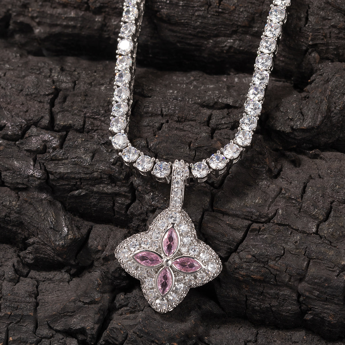 Pink four-leaf clover pendant displayed against dark textured wood