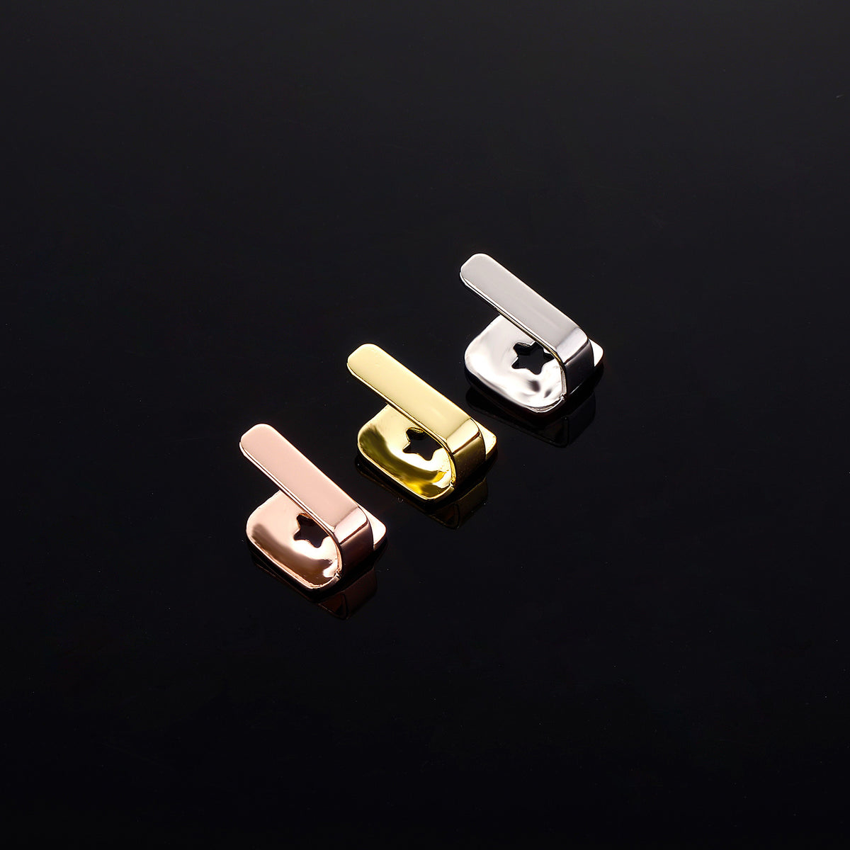 Rose Gold, Gold and Silver bar tooth caps showing their backs on a black surface