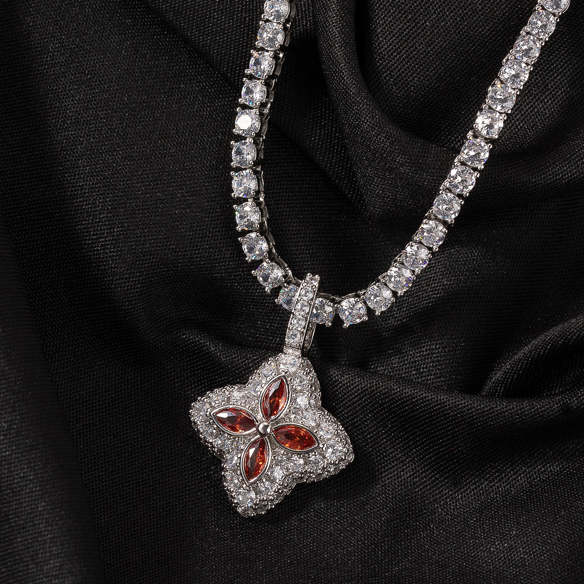 Ruby-red four-leaf clover pendant displayed on black fabric