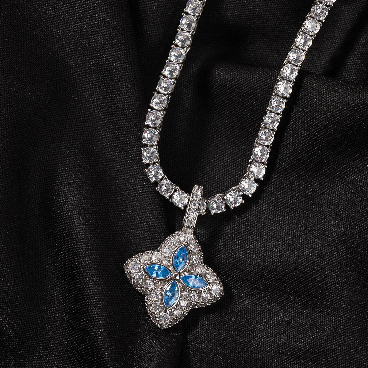 Aqua-blue four-leaf clover pendant displayed on black fabric